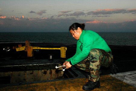 US Navy 091218-N-3327M-025 Aviation Boatswain's Mate (Equipment) Airman Martina Camacho applies grease to the bolts on a catapult aboard the aircraft carrier USS Nimitz (CVN 68) photo