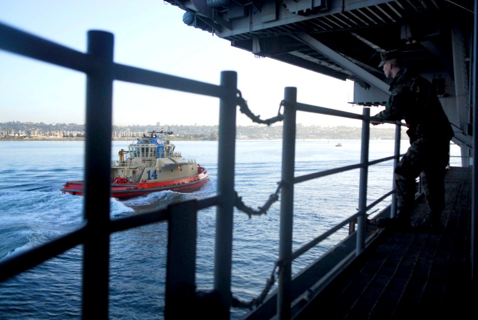 US Navy 091214-N-2475A-091 Gunner's Mate 3rd Class Michael Milligan looks out at San Diego as a tug boat guides the ship to a pier