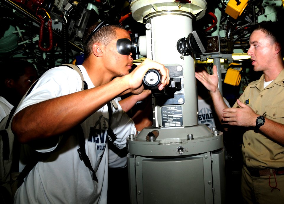 US Navy 091223-N-3560G-002 Ensign Tom Kerman, assigned to the Los Angeles attack submarine USS Tucson (SSN 770), explains periscope operations to members of the University of Nevada football team during a tour of the boat