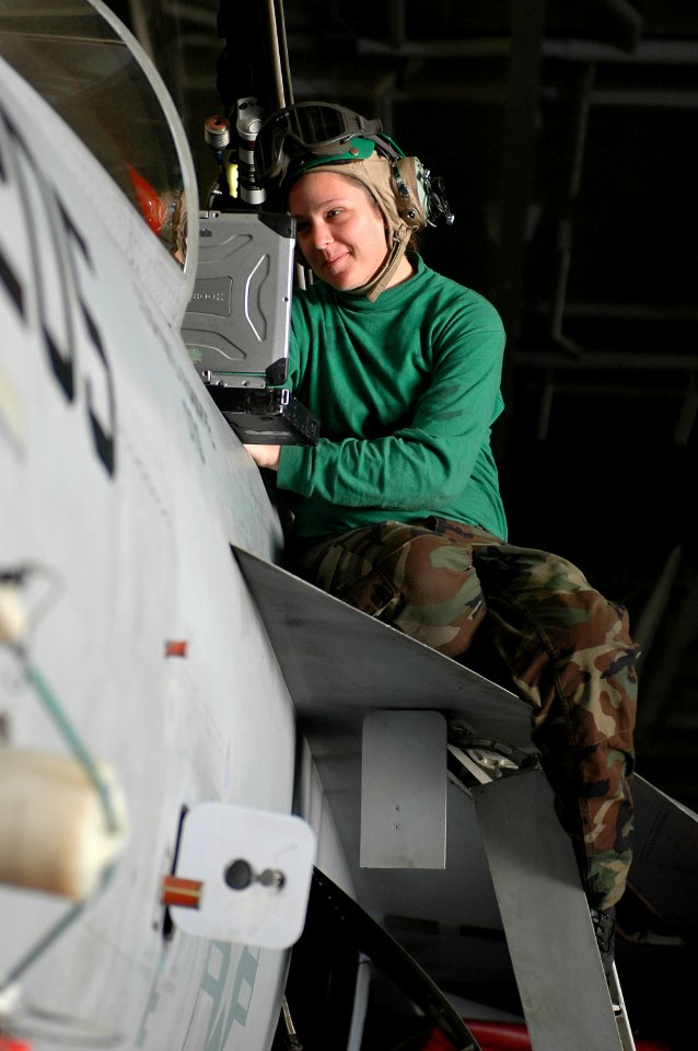 US Navy 091224-N-7939W-003 viation Electronics Technician 3rd Class Marlana Keller, assigned to the Tophatters of Strike Fighter Squadron (VFA) 14, reads out instructions for wire repair on an F-A-18E Super Hornet