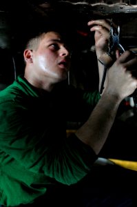 US Navy 091224-N-7939W-050 Aviation Machinist's Mate Seaman Christopher King, assigned to the Warhawks of Strike Fighter Squadron (VFA) 97, conducts maintenance on wiring on an F-A-18C Hornet aboard the aircraft carrier USS Nim