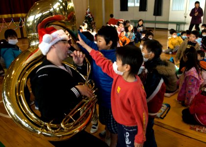 US Navy 091221-N-8721D-077 Musician Petty Officer 2nd Class James Brownell draws a crowd of children during a free holiday concert at Ogusu Elementary
