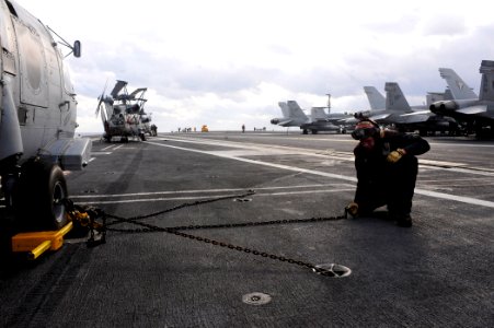 US Navy 100105-N-6604E-007 Aviation Machinist's Mate Airman John Wagner connects a tiedown chain to a padeye on the flight deck of the aircraft carrier USS Dwight D. Eisenhower (CVN 69)