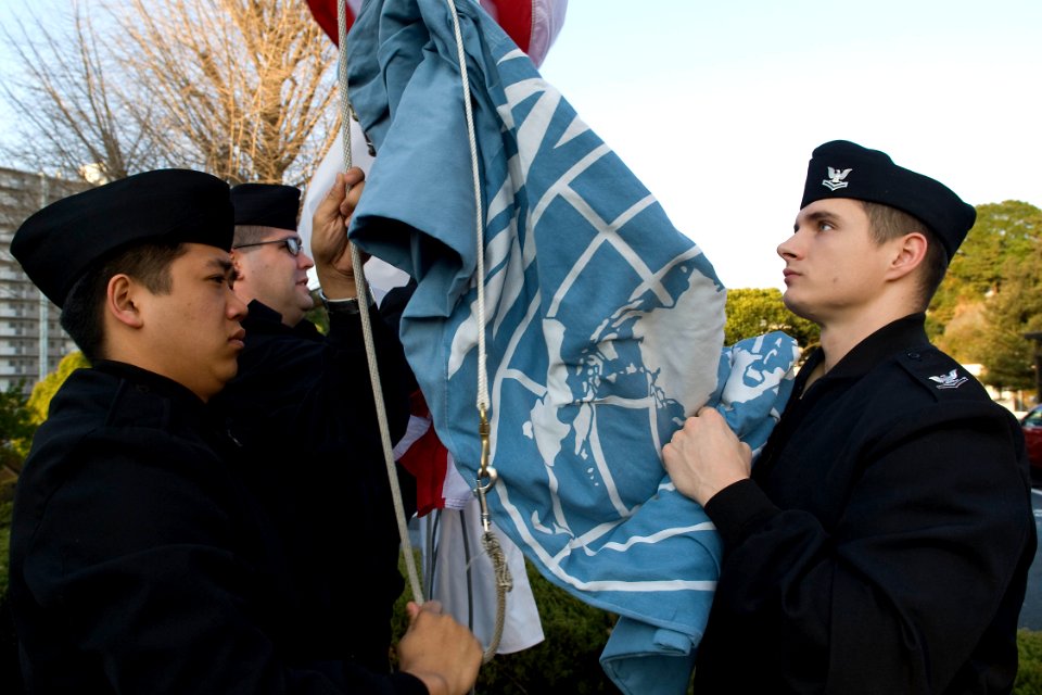 US Navy 100105-N-9123L-016 Personnel Specialist Seaman Adam Dickey and Machinist's Mate 2nd Class Jonathan Kress raise the United Nations flag during morning colors at Fleet Activities Yokosuka