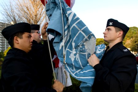 US Navy 100105-N-9123L-016 Personnel Specialist Seaman Adam Dickey and Machinist's Mate 2nd Class Jonathan Kress raise the United Nations flag during morning colors at Fleet Activities Yokosuka