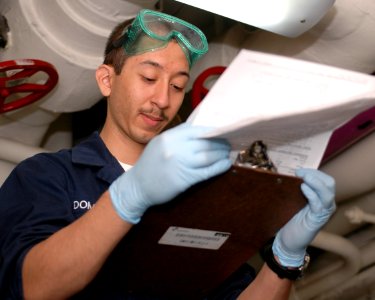 US Navy 100104-N-7939W-009 Logistics Specialist Seaman Ezequiel Dominguez reviews maintenance instructions for a hatch aboard the aircraft carrier USS Nimitz (CVN 68)