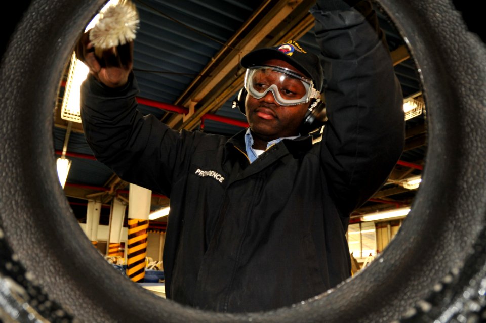 US Navy 100107-N-4031K-011 Aviation Support Equipment Technician 2nd Class Winston Providence, assigned to Aircraft Intermediate Maintenance Detachment, lubes a tire before rebuilding a rear tow tractor tire assembly at Naval A