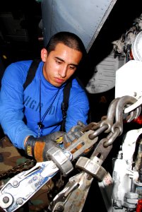 US Navy 100114-N-3327M-044 Aviation Boatswain's Mate (Handling) Airman Julio Velasquez chains down an F-A-18C Hornet