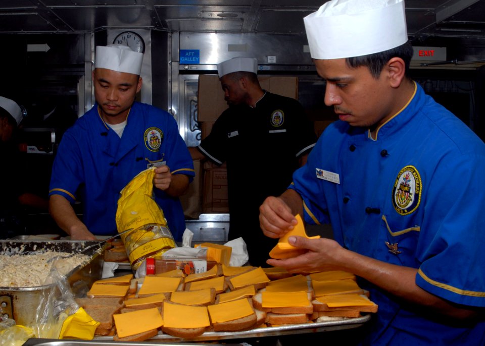 US Navy 100107-N-8607R-052 Culinary Specialist Seaman Dequan Luo and Culinary Specialist 3rd Class Ricardo Carreon prepare tuna melt sandwiches in the main galley aboard USS Bonhomme Richard (LHD 6)