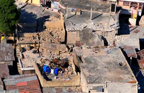 US Navy 100115-N-4774B-643 A man clears away rubble while an SH-60F Sea Hawk helicopter flies overhead as part of relief efforts in Haiti