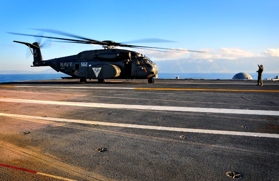 US Navy 100115-N-4774B-030 On board the Nimitz-class aircraft carrier USS Carl Vinson (CVN 70), a flight deck crew member signals to an MH-53E Sea Dragon carrying water and supplies to Haiti relief efforts
