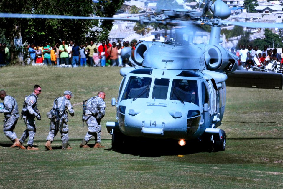 US Navy 100116-D-1852B-051 U.S. Army Soldiers unload food and water from a U.S. Navy SH-60 Sea Hawk helicopter from the aircraft carrier USS Carl Vinson (CVN 70) in Port-au-Prince, Haiti