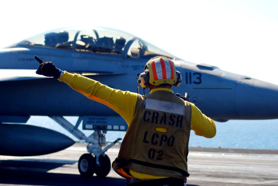 US Navy 100118-N-3589B-011 A flight deck director signals to an F-A-18C Hornet assigned to the Sidewinders of Strike Fighter Squadron (VFA) 86