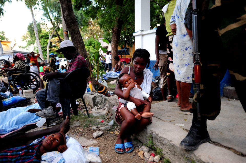 US Navy 100116-N-2953W-385 A Haitian mother comforts her child at the Killick Haitian Coast Guard Base clinic as a member of the U.N. security team stands watch