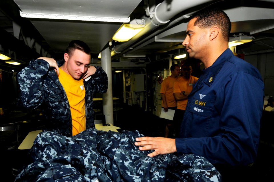 US Navy 100117-N-3038W-033 Chief Air-Traffic Controller Loren Brown assists Air-Traffic Controller 3rd Class Anthony Schlund with fitting the new navy working uniform aboard the aircraft carrier USS Nimitz (CVN 68)