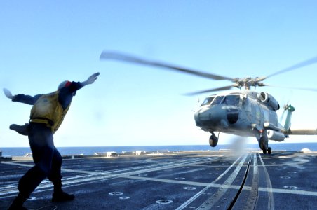 US Navy 100117-N-4124C-003 Boatswain's Mate Seaman Rueben Benders, from the Dominican Republic, guides an SH-60H Sea Hawk helicopter to land aboard the guided-missile cruiser USS Normandy (CG 60)