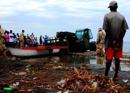 US Navy 100119-N-5244H-015 A fisherman watches as members of Beach Master Unit (BMU) 2 clear a damaged boat away from the shoreline to make way for landing craft air cushion vehicles transporting heavy equipment and supplies