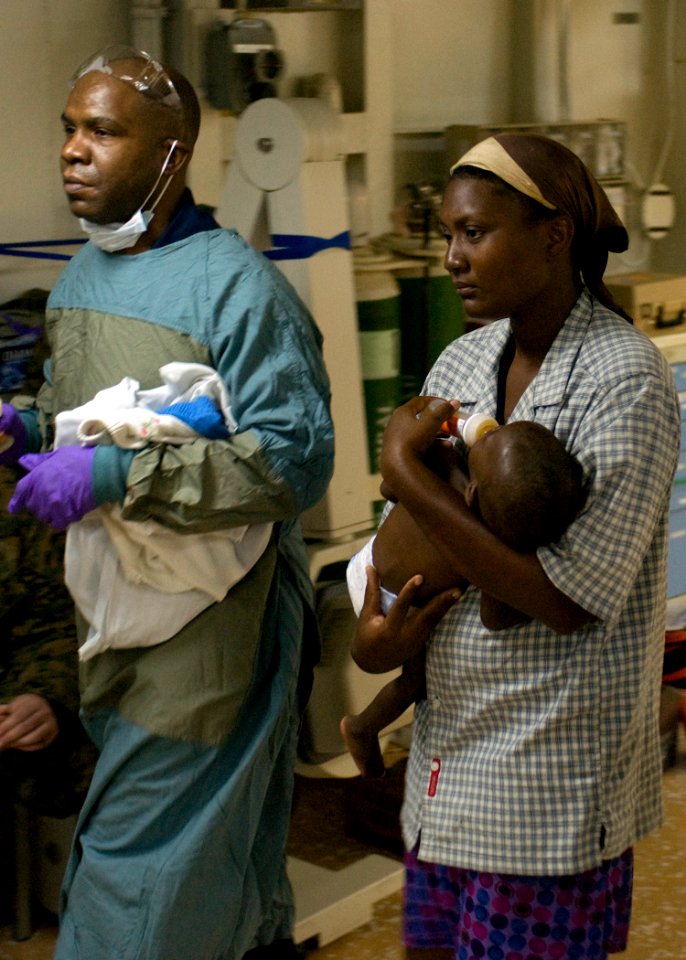 US Navy 100119-N-3165S-218 A mother carries her nine-month old son aboard the multi-purpose amphibious assault ship USS Bataan (LHD 5) after the child was airlifted to the ship for medical treatment