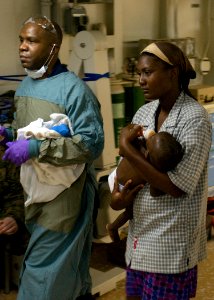 US Navy 100119-N-3165S-218 A mother carries her nine-month old son aboard the multi-purpose amphibious assault ship USS Bataan (LHD 5) after the child was airlifted to the ship for medical treatment photo