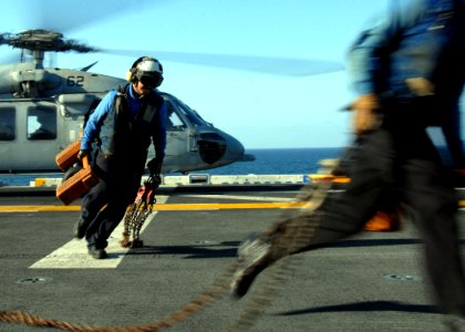 US Navy 100118-N-0515W-013 Aviation Boatswain's Mate (Handling) Airman Miguel Melendres removes chocks and chains from SH-60 Sea Hawk helicopter aboard the amphibious assault ship USS Bonhomme Richard (LHD 6) during flight oper
