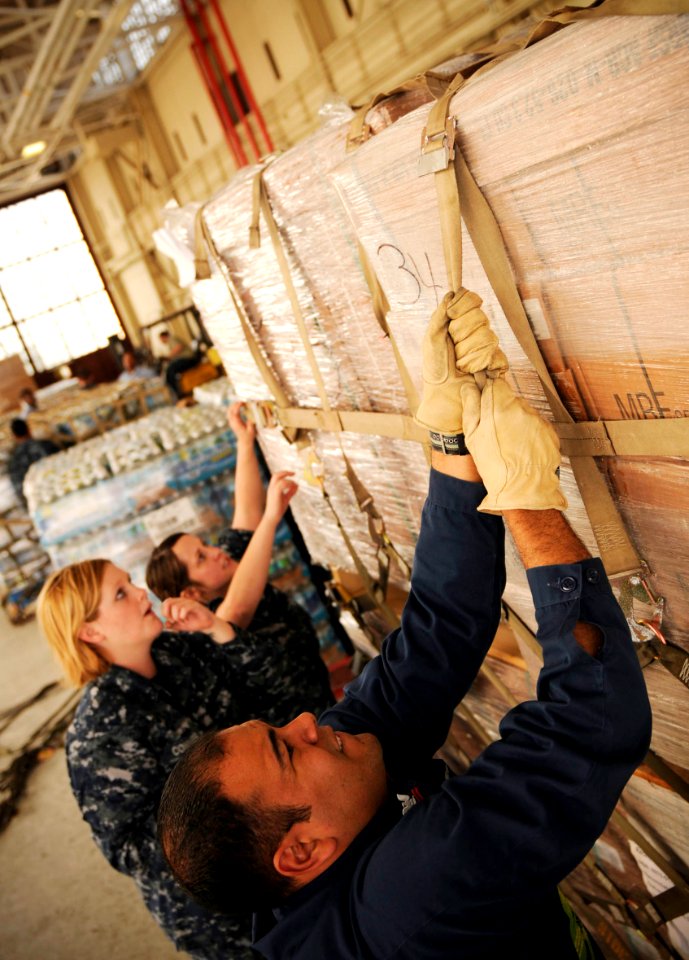 US Navy 100117-N-8590G-004 Yeoman 2nd Class Carlos Agosto-Baez, front, Aviation Ordnanceman Airman Caitlin Conner, and Seaman Jessica McClarney from Naval Air Station Jacksonville, load pallets containing food and water for tra