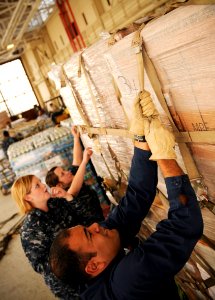 US Navy 100117-N-8590G-004 Yeoman 2nd Class Carlos Agosto-Baez, front, Aviation Ordnanceman Airman Caitlin Conner, and Seaman Jessica McClarney from Naval Air Station Jacksonville, load pallets containing food and water for tra photo