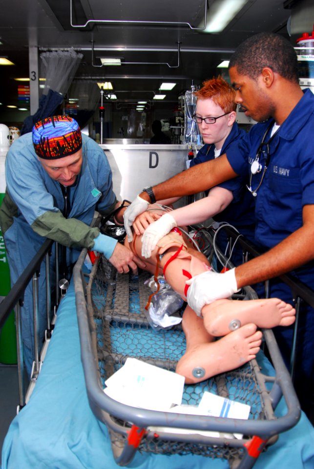 US Navy 100119-N-4047W-005 Hospitalman Kwesi Williams and Hospital Corpsman 3rd Class Alexis Albright help Cmdr. Zsolt Stockinger move a mannequin from a stretcher to a gurney