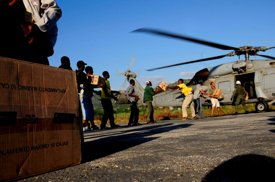 US Navy 100118-N-6006S-045 Air crew members are assisted by United Nations volunteers and Haitian citizens during a food and supply drop off
