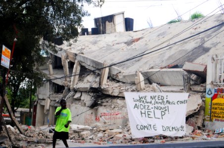 US Navy 100119-N-8878B-322 A Haitian man walks past a sign requesting help and supplies in Port-au-Prince, Haiti photo