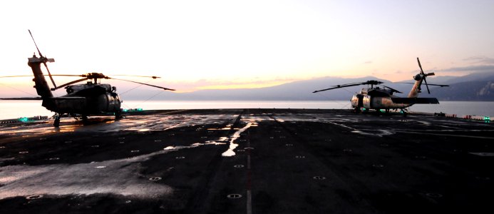 US Navy 100119-N-1092P-063 he SH-60 Sea Hawk helicopters are on the flight deck of the amphibious assault ship USS Bataan (LHD 5) as the sun rises over Haiti