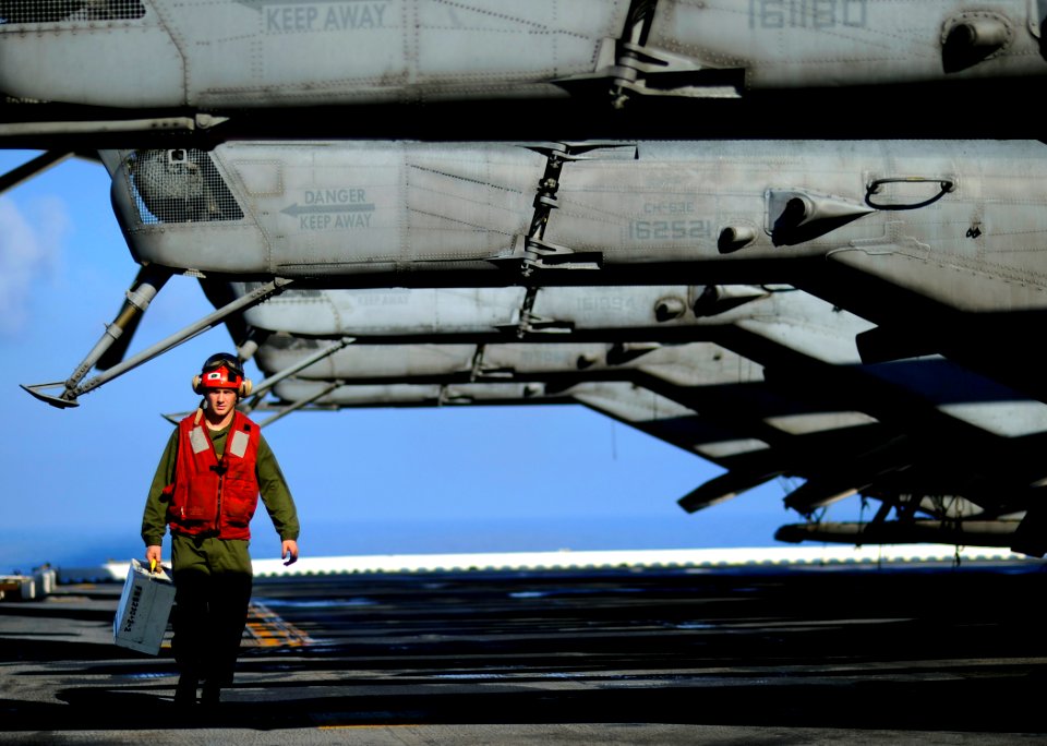 US Navy 100118-N-5345W-032 Lance Cpl. Timothy Smith, assigned to the Sabers of Marine Light Attack Helicopter Squadron (HMLA) 467 crosses the flight deck unde