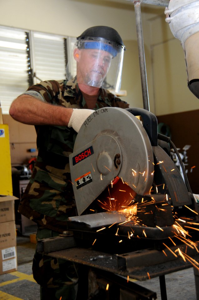 US Navy 100120-N-1906L-003 aster-at-Arms 2nd Class David Melia, from Navy Cargo Handling Battalion (NCHB) 7, cuts through a piece of metal to build signs at the U.S. Naval Base Guam Fuel Farm Division