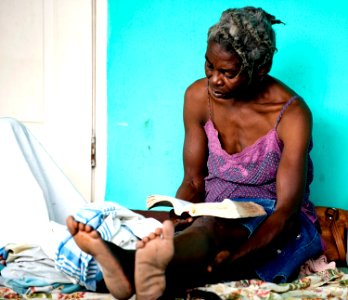 US Navy 100119-N-6266K-090 An elderly Haitian woman reads the Bible while waiting for medical treatment at Gheskio Field Hospital in Haiti photo