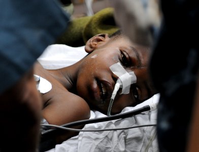 US Navy 100119-N-4995K-125 Medical professionals aboard the Military Sealift Command hospital ship USNS Comfort (T-AH 20) treat a six-year-old Haitian boy in the casualty receiving room photo