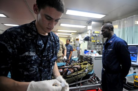 US Navy 100119-N-4995K-187 Hospital Corpsman 3rd Class Adam Buzzeo prepares medical equipment during the assessment of a six-year-old Haitian boy brought aboard the Military Sealift Command hospital ship USNS Comfort (T-AH 20) photo