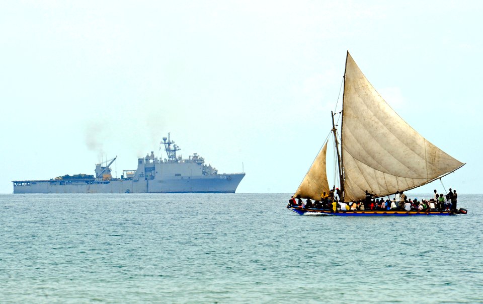 US Navy 100119-N-5345W-110 A Haitian boat sails off the coast of Haiti as the amphibious dock landing ship USS Carter Hall (LSD 50) operates in the distance