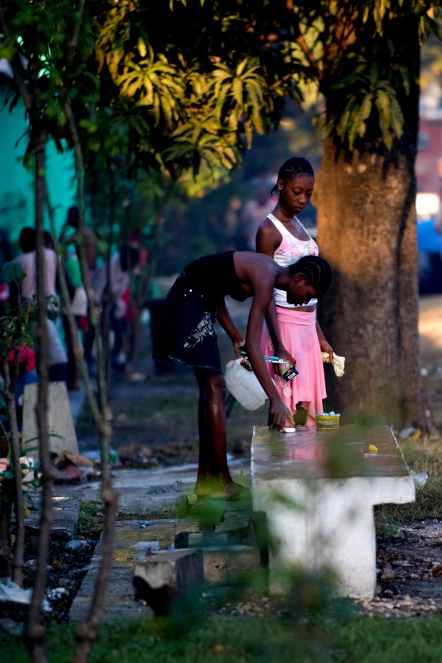 US Navy 100119-N-6266K-027 Two young Haitian women wash themselves outside their make-shift home outside Gheskio Field Hospital in Haiti
