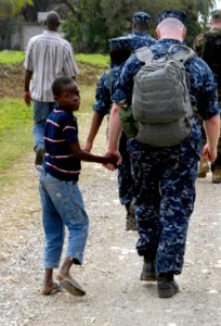 US Navy 100119-N-7653W-186 Chaplin Stephen Warne walks with a Haitian citizen through a village in Port-Au Prince, Haiti