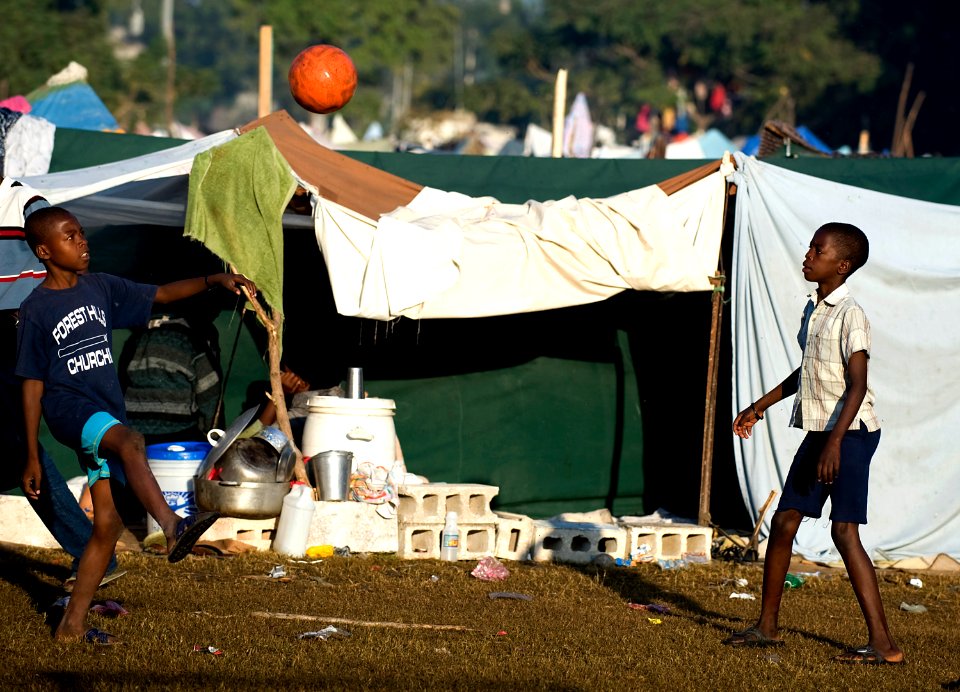 US Navy 100119-N-6266K-044 Two Haitians boys play soccer amongst make-shift homes outside Gheskio Field Hospital in Haiti