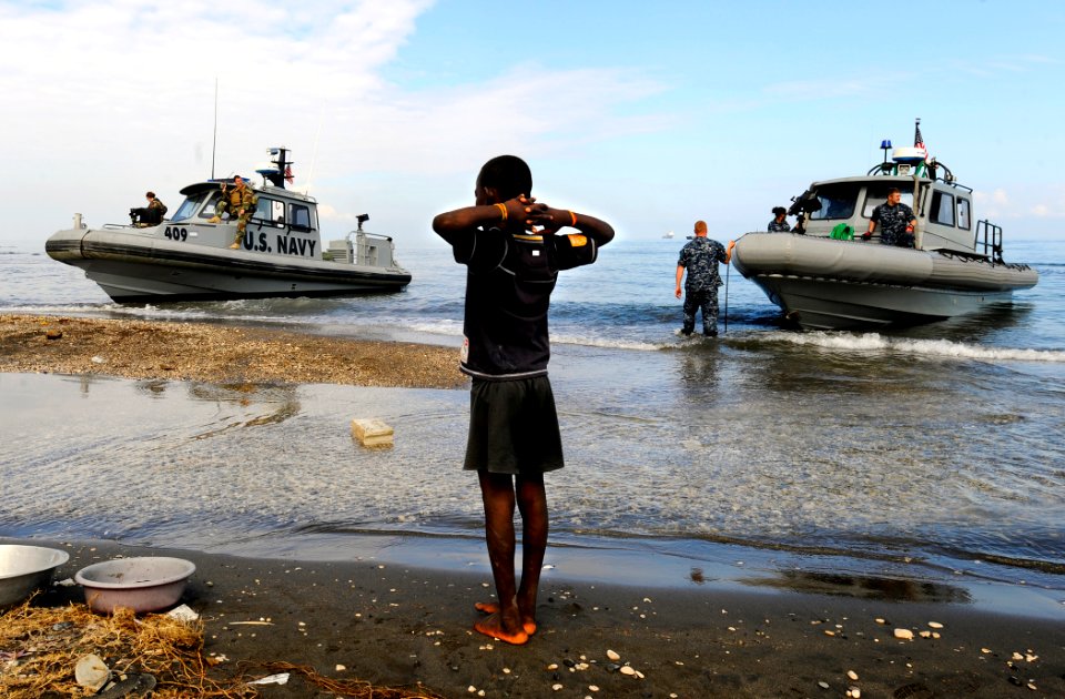 US Navy 100119-N-5345W-041 A Haitian boy watches as rigid-hull inflatable boats from the amphibious dock landing ships USS Fort McHenry (LSD 43) and USS Carter Hall (LSD 50) arrive ashore at the New Hope Mission at Bonel, Haiti