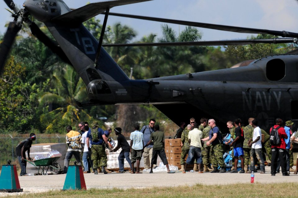 US Navy 100120-N-4995K-179 Canadian soldiers and Haitian citizens unload food and water from an MH-53E Sea Dragon helicopter