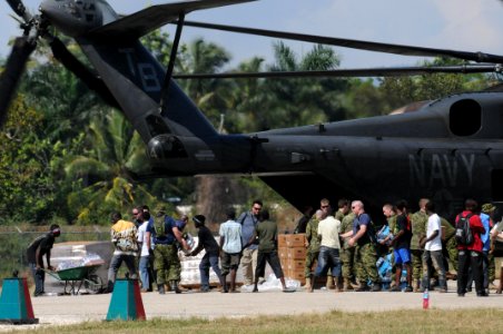 US Navy 100120-N-4995K-179 Canadian soldiers and Haitian citizens unload food and water from an MH-53E Sea Dragon helicopter