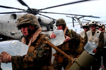 US Navy 100119-N-7508R-040 Marines carry bottles of water to load onto a CH-53E Super Stallion helicopter aboard USS Bataan (LHD 5) photo