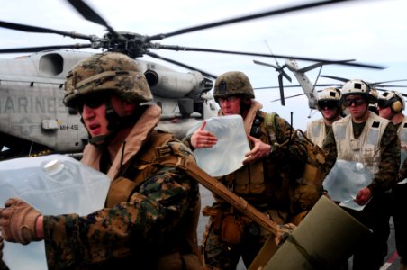 US Navy 100119-N-7508R-040 Marines carry bottles of water to load onto a CH-53E Super Stallion helicopter aboard USS Bataan (LHD 5)
