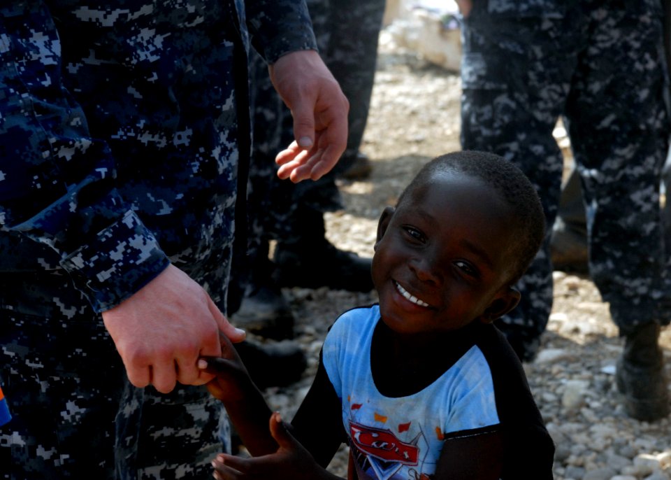 US Navy 100120-N-2000D-008 A Haitian boy holds the hand of a Sailor assigned to the Bataan Amphibious Relief Mission