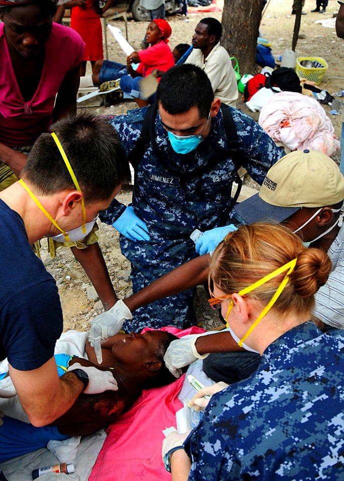US Navy 100119-N-6247V-925 Lt. Aaron Boney (left), assigned to the aircraft carrier USS Carl Vinson (CVN 70), checks a Haitian boy for additional injuries at the Killick