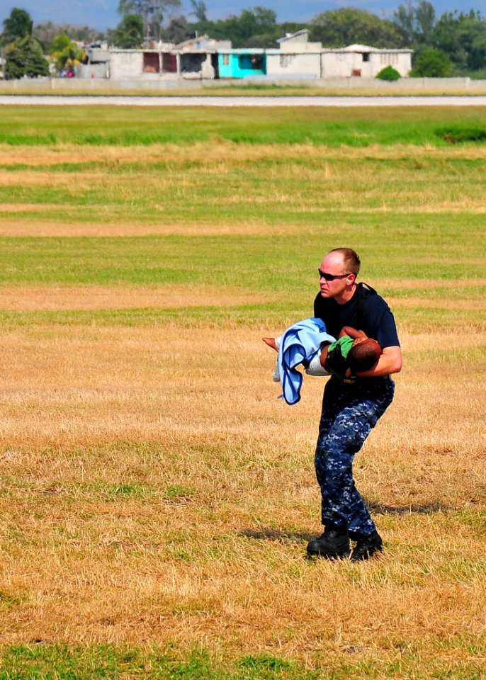 US Navy 100120-N-4774B-226 Chief Aviation Support Equipment Technician William Cross carries a Haitian child in need of medical assistance