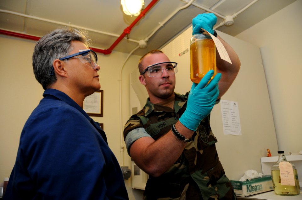 US Navy 100120-N-1906L-002 Master-at-Arms 2nd Class Morgan Mohr and Grace Rosier, a physical science technician at Naval Base Guam, perform an appearance test on a sample of jet fuel to determine the existence of impurities
