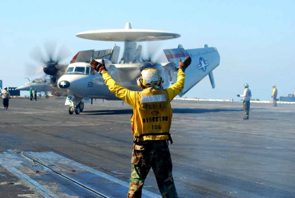 US Navy 100120-N-3589B-101 A flight deck director signals to an E2-C Hawkeye assigned to the Wallbangers of Carrier Airborne Early Warning Squadron (VAW) 117 during flight operations aboard the aircraft carrier USS Nimitz (CVN