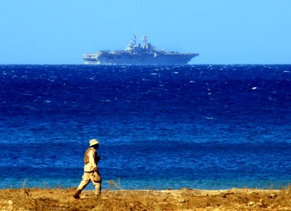 US Navy 100122-N-7508R-050 The multi-purpose amphibious assault ship USS Bataan (LHD 5) operates off the coast of Haiti as a Sailor patrols a Haitian beach. Bataan, along with the amphibious dock landing ships USS Fort McHenry